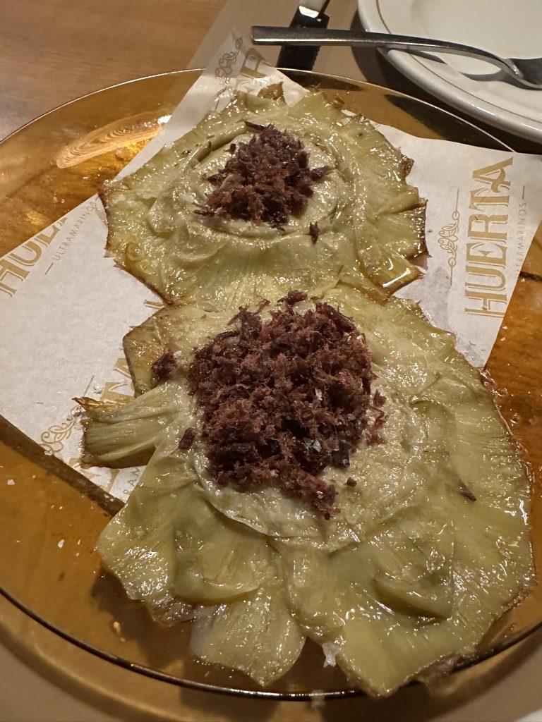 Alcachofas confitadas con cecina, plato gourmet de texturas contrastantes.