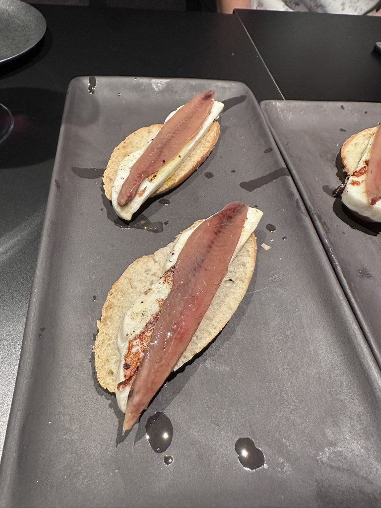 Plato de Anchoas López “Serie Oro” servido con aceite de oliva virgen extra sobre plato blanco.