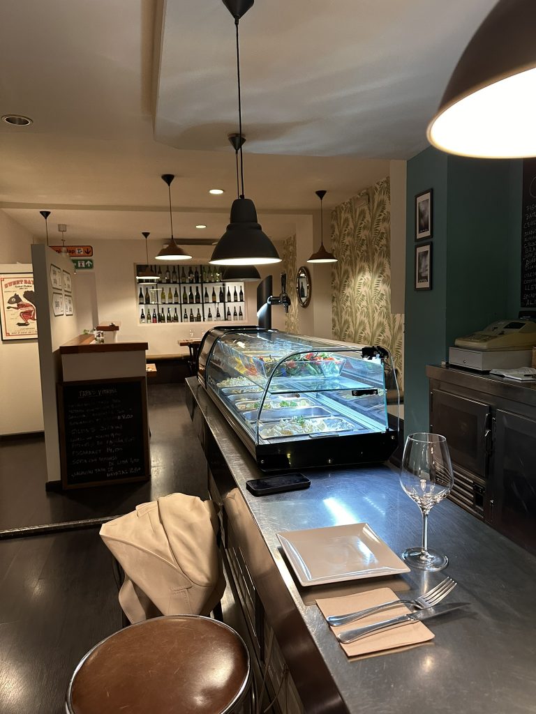 Vista de la barra metálica de Boucan Winebar con iluminación cálida y botellas al fondo