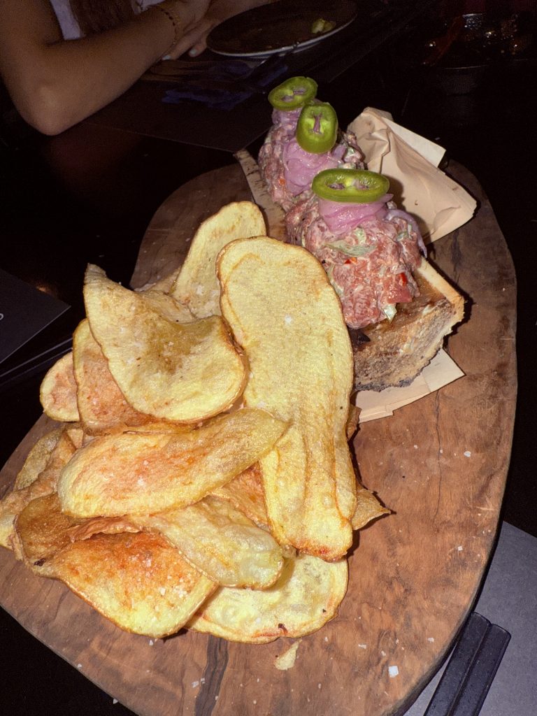 Plato de beef tartar en El Cerdo Negro 1985, servido con jalapeños frescos y chips crujientes sobre una tabla de madera