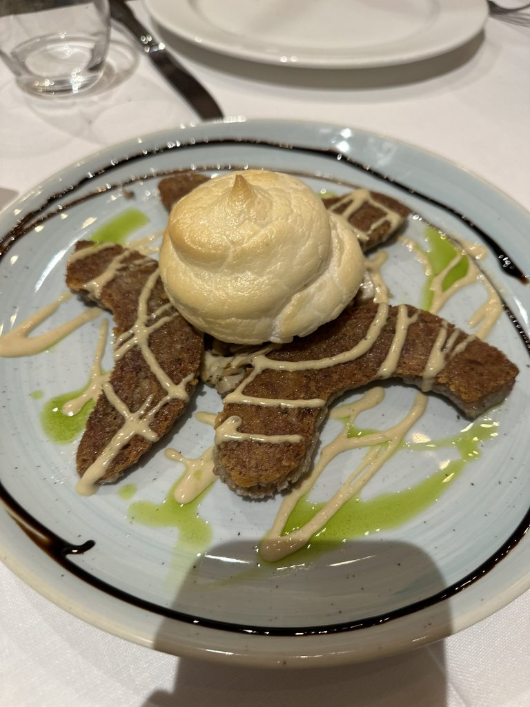 Un plato de butifarra de perol con níscalos confitados y crujiente de clara a la mostaza, una delicia de la cocina de montaña.