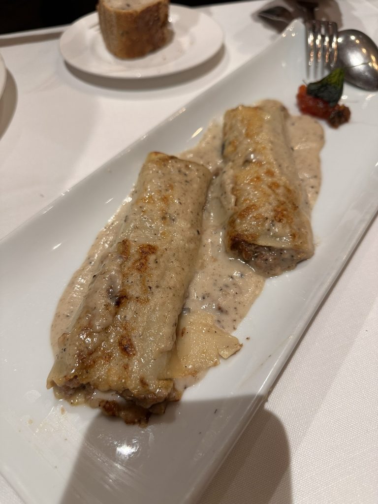 Un plato de canelón casero de oca del Gers con confitura de tomate y colmenillas, ingredientes locales en una creación culinaria única.