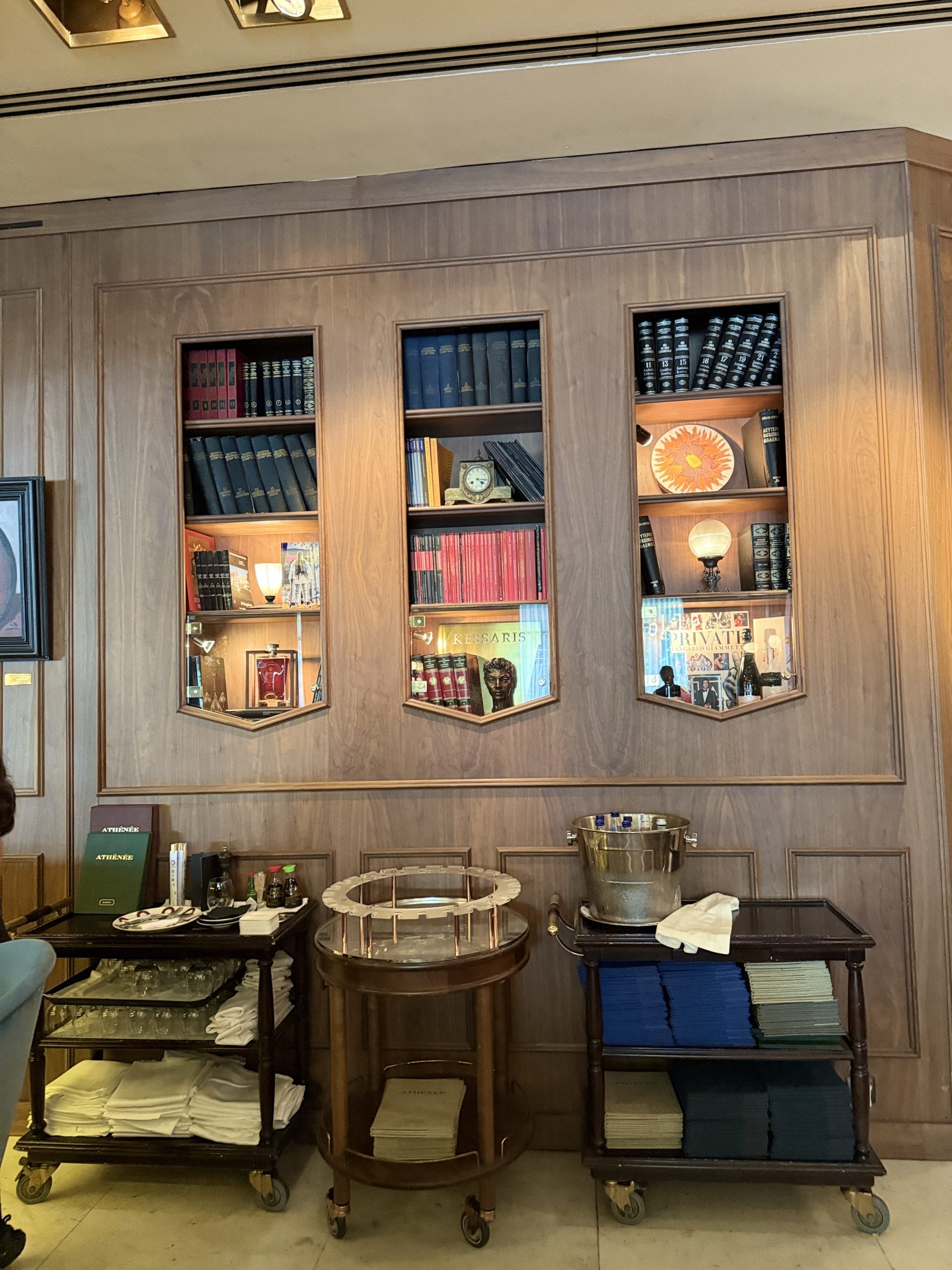 Estantería decorativa en el interior de Athénée con libros, vajilla y fotografías