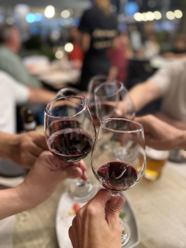 Mano brindando con una copa de vino tinto local durante la cena en el restaurante L'Angolino en Riccione