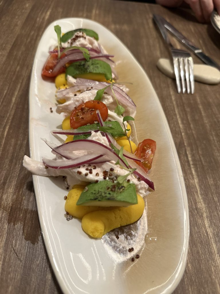 Una porción de causa limeña, mostrando capas de puré de patata amarilla, pollo desmenuzado, aguacate y mayonesa de hierbas aromáticas.