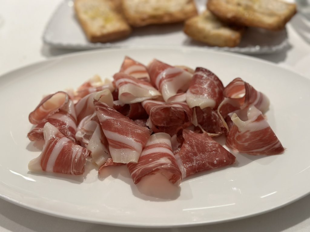 Plato de jamón ibérico de bellota cortado a mano, acompañado de pan tostado y aceite de oliva virgen extra.