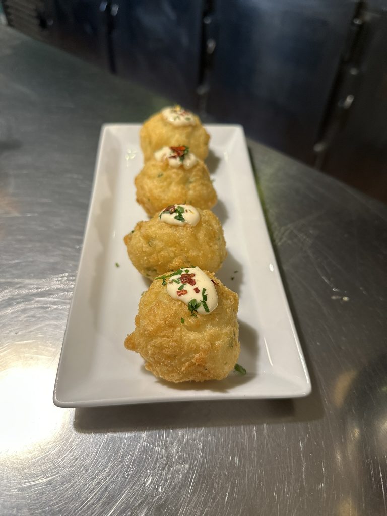 Buñuelos de bacalao crujientes por fuera y cremosos por dentro, servidos como tapa en Boucan Winebar