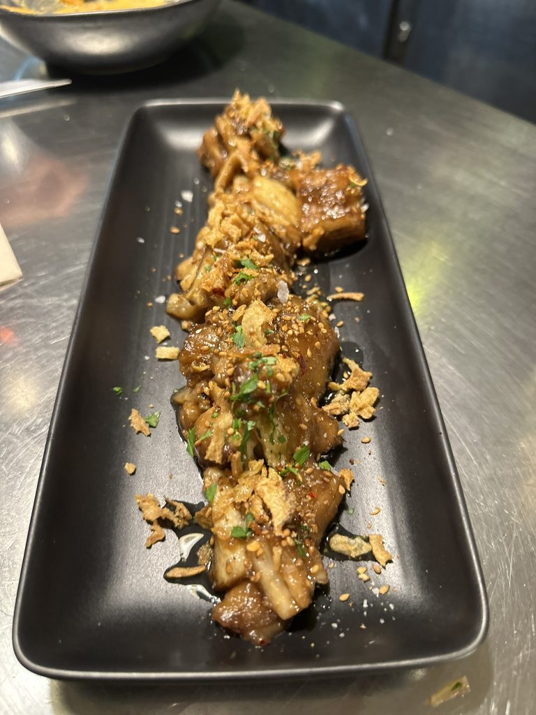 Berenjenas asadas a la llama con aliño mediterráneo y presentación rústica en Boucan Winebar