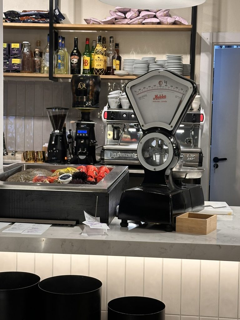 Interior de Informal VADEBO, Valencia, con pescado fresco y báscula antigua, destacando el contraste entre lo clásico y lo moderno