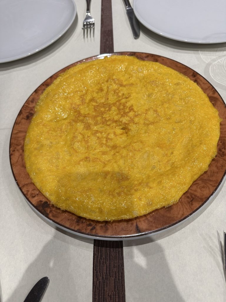 Primer plano de una tortilla de patata dorada y jugosa en Casa Peru, Bagergue.
