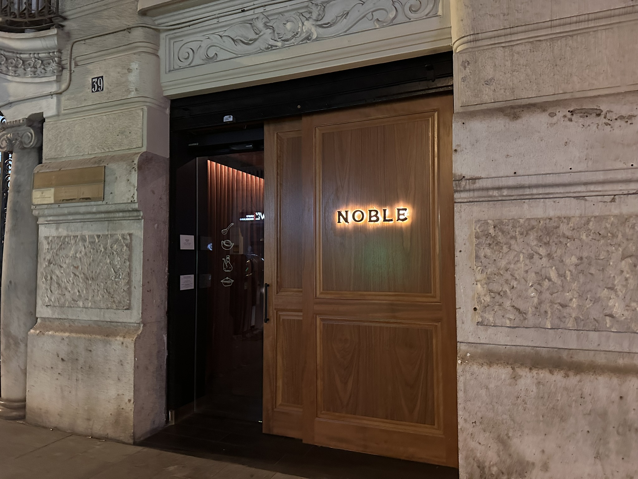 ELegante puerta de madera con el cartel del Restaurante Noble en Valencia