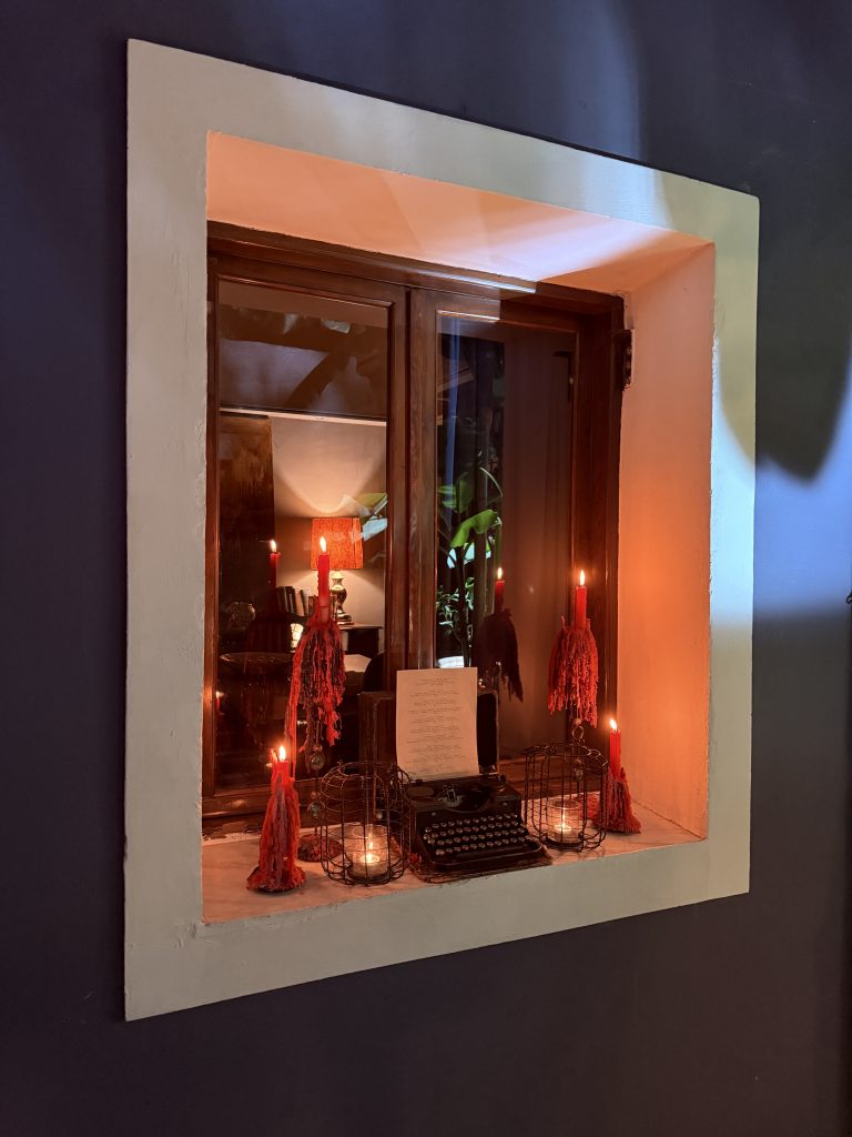 Detalle del interior de la terraza de El Cerdo Negro 1985, con una máquina de escribir antigua apoyada sobre la pared y velas encendidas en un ambiente tenue
