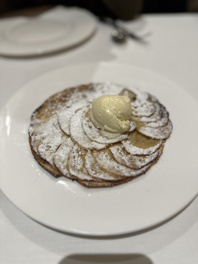 Una porción de tarta fina de manzana con crema helada de vainilla, un postre clásico y delicioso.