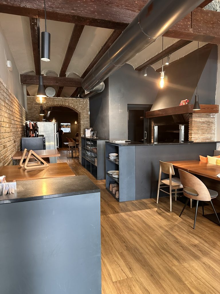 Fotografía desde la entrada de Basea Restaurante donde se aprecia la parrilla abierta y la sala interior en Valencia